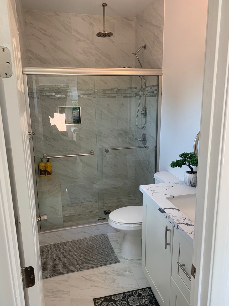 Finished walk-in shower with marble-look tile and glass door