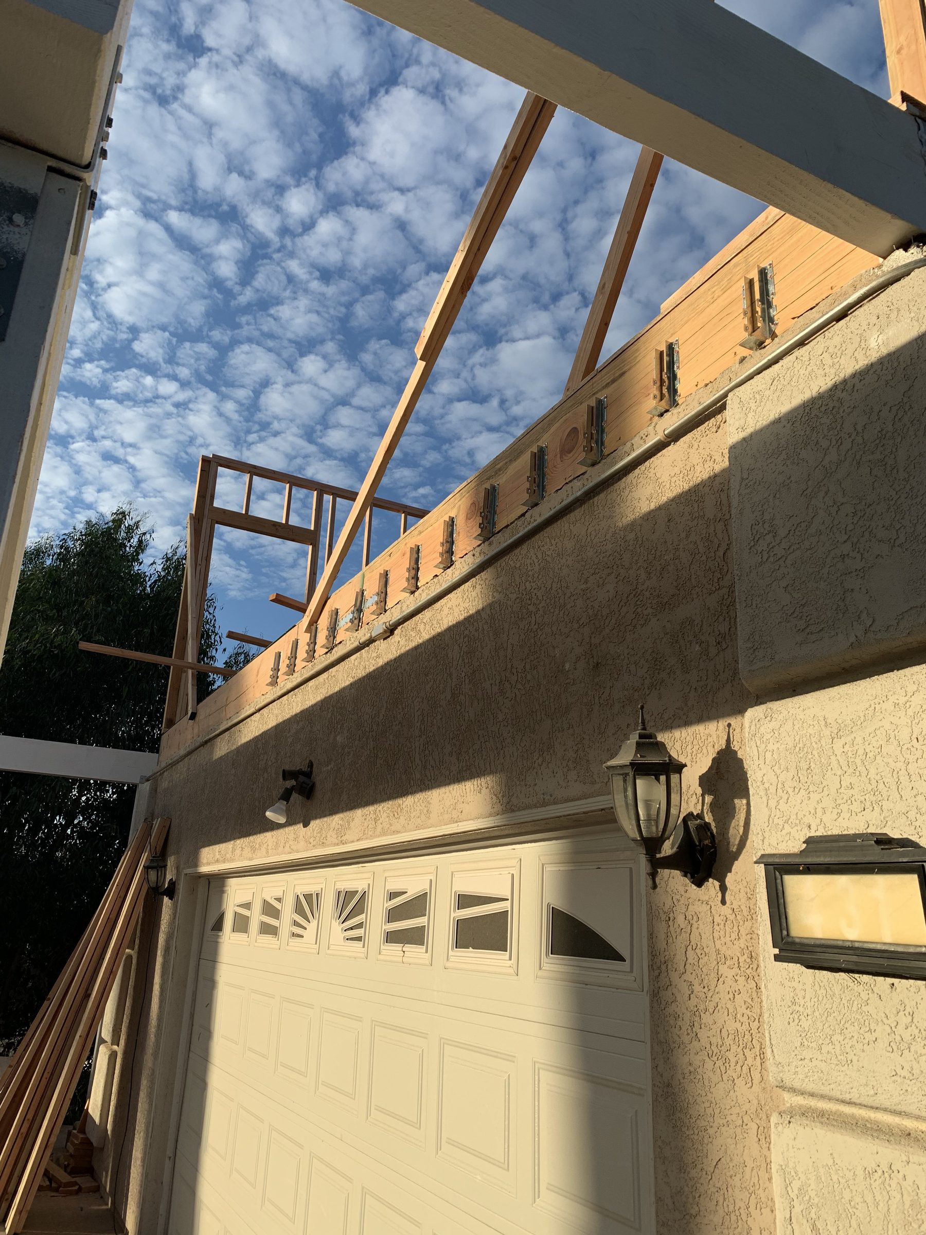 Looking up past new second-story framing into a cloud-filled sky